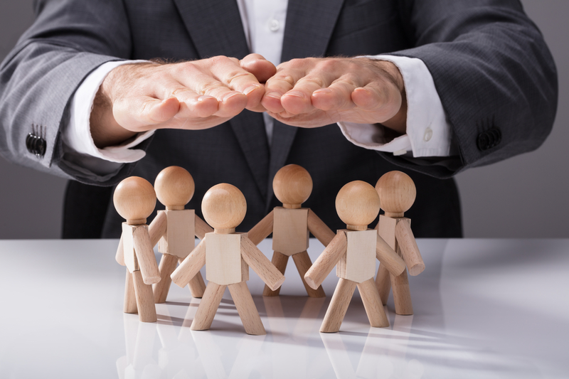 Human Hand Protecting Wooden Figures On White Background Human Hand Protecting Wooden Figures On White Background